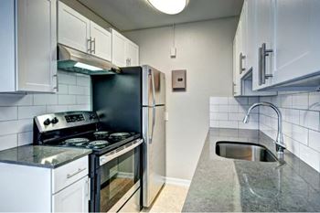 A kitchen with a black refrigerator, stove, and oven.